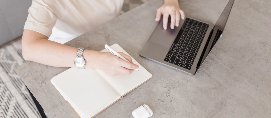 Eine Person arbeitet am Laptop und macht sich Notizen als Vorbereitung auf die Erstellung einer barrierefreien Website.
