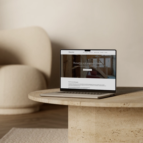 Mockup-Website-FerienwohnungenMaijeschhofPelm Laptop auf einem Tisch, auf dem die WordPress Website des Maijeschhofs in Pelm angezeigt wird.