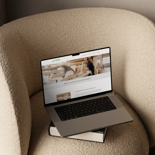 Mockup-Website-ThomasRieder Leonie Rieder, eine junge Frau mit dunkelblonden Haaren, sitzt auf dem Boden und schaut in ein Laptop. Sie trägt ein weißes Oberteil, einen hellbraunen Blazer und eine schwarze Hose.