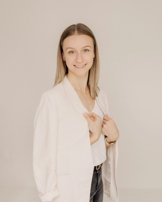 WEBSITEmastery-LeonieRieder Bild der WordPress Expertin Leonie Rieder, die vor einem neutralen Hintergrund steht und einen hellen Blazer mit einem weißen T-Shirt trägt.